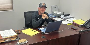 Man in cap at desk with laptop